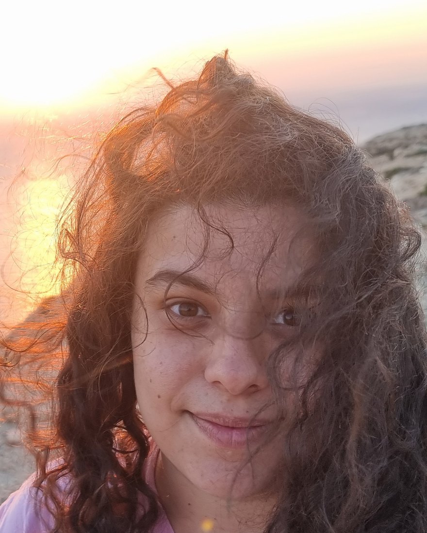 Portrait of Elli Zafeiridou Georgiadou, outdoors by the sea at sunset